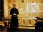 Father Bernard Brown standing in front of restored Old Catholic Mission altar (shutters closed)