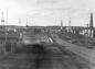 A view of Little Chicago, the main road, some cars, and oil derricks