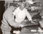 Mr. Fred Kerr and a trapper measuring an animal skin on a counter.