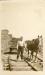 A lumber mill employee with a horse, hailing lumber on a cart along the railroad tracks.