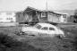 A 1950's sedan and a hald cedar shake house damaged by the tsunami