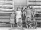 Les nombreux enfants d'une famille de colons sur la galerie de la maison de bois rond