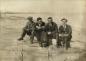 Ben Konrad, Abe Konrad, Jake Gossen & Nick Wiens sitting on a log at the beach on a Sunday afternoon